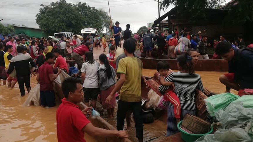 Crowds of people stand on boats in flooded streets.