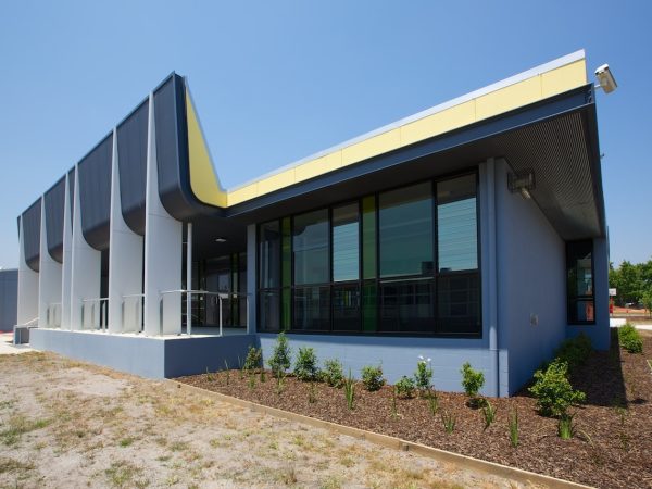 An artists impression of a blue building with small trees lining 
