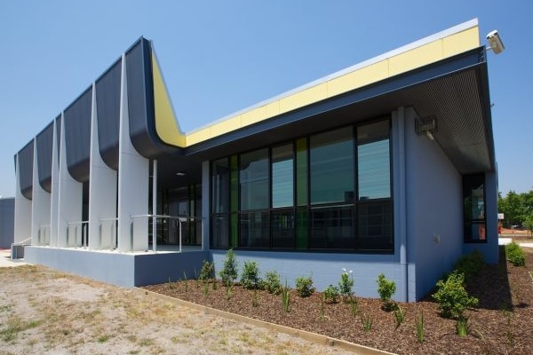 An artists impression of a blue building with small trees lining 