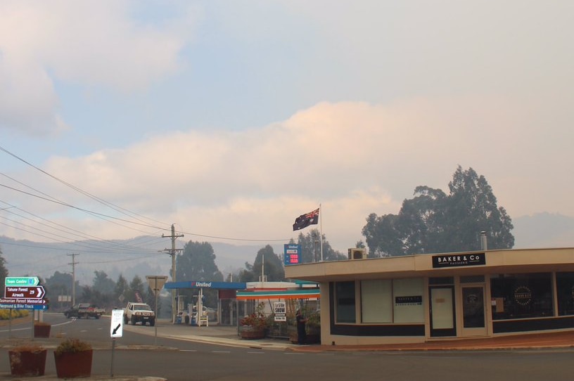 A flag flies in Geeveston on Australia Day, as smoke from a nearby bushfire lingers in the air
