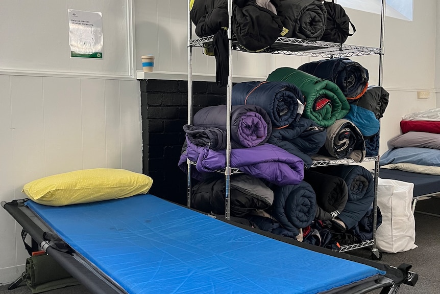Camp stretcher and bed rolls on a storage rack at a homeless shelter.