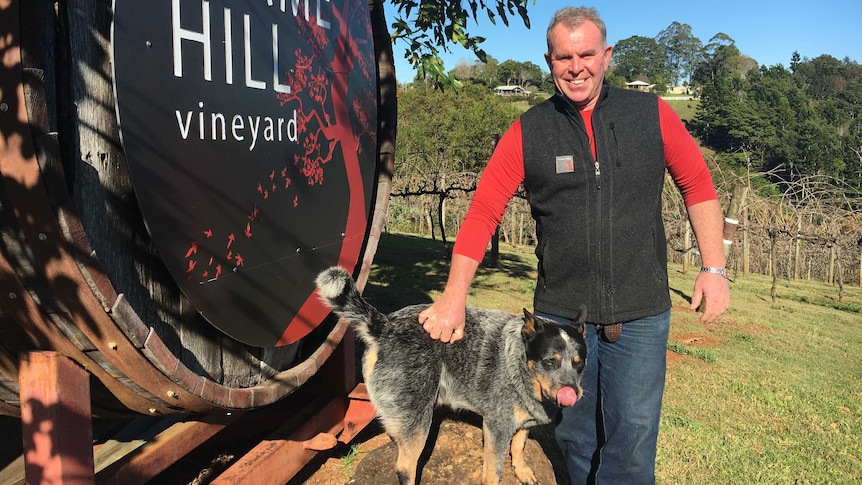 Tony Thompson poses with his cattle dog Bill at the entrance to Flamehill vineyard