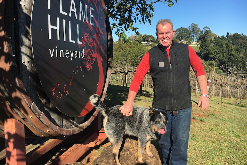 Tony Thompson poses with his cattle dog Bill at the entrance to Flamehill vineyard