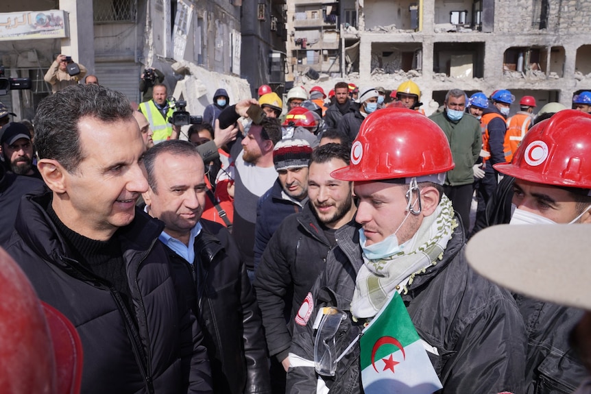 Bashar Al Assad grins at rescue workers