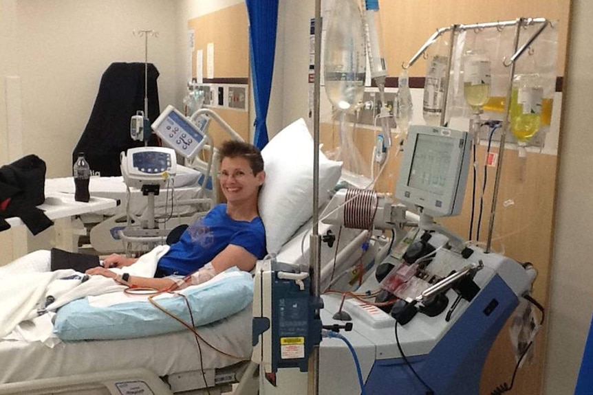 A smiling woman is hooked up to machines in a hospital