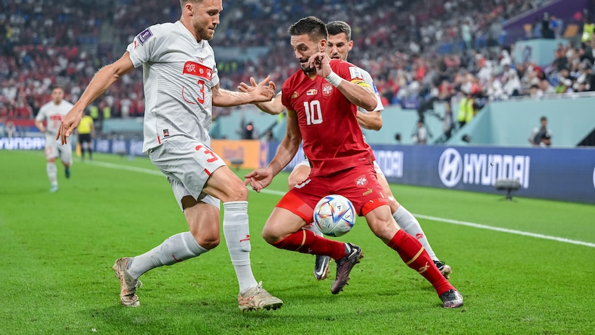 Dusan Tadic dribbles the ball under pressure from two Swiss defenders