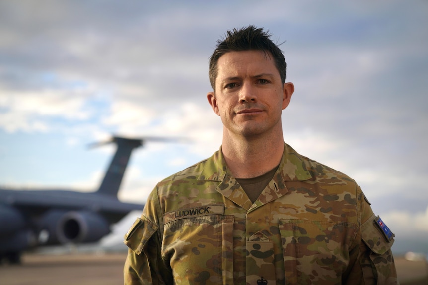 A portrait of an Australian Army officer standing in front of a military airplane.