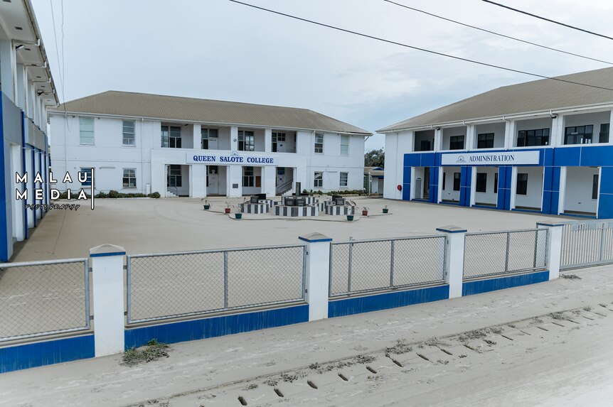 Three white buildings of a school yard with blue trimmings, in Tonga. 
