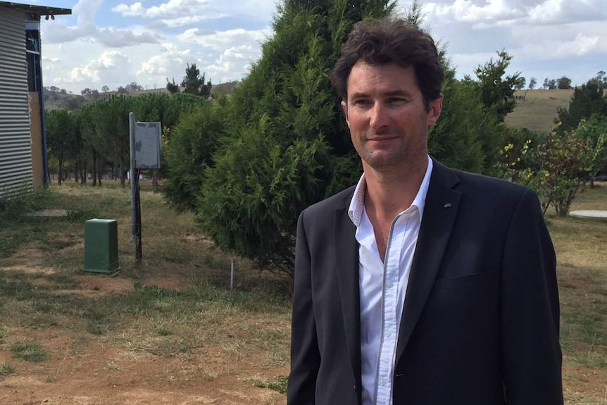 Damian De Marco stands in a paddock outside his home.