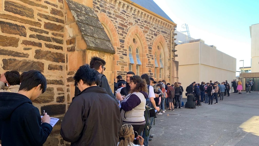 A line of people next to buildings