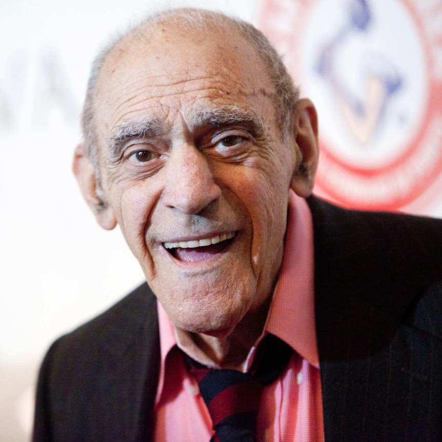 Headshot of Abe Vigoda smiling while he is being photographed on the red carpet in 2012.