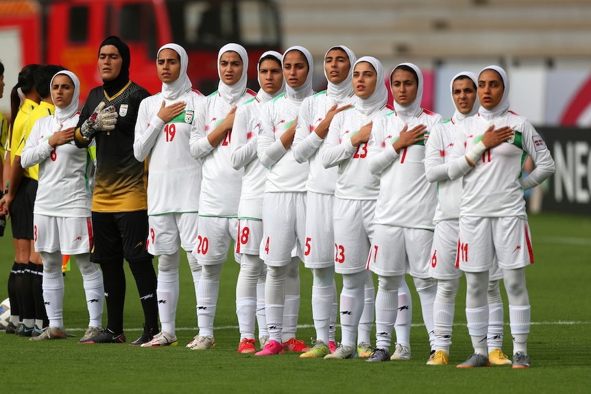 Women soccer players line up for the national anthem