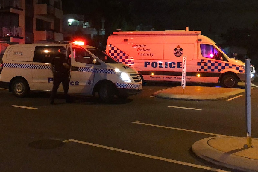 A mobile police facility van and a police car at a suburban intersection