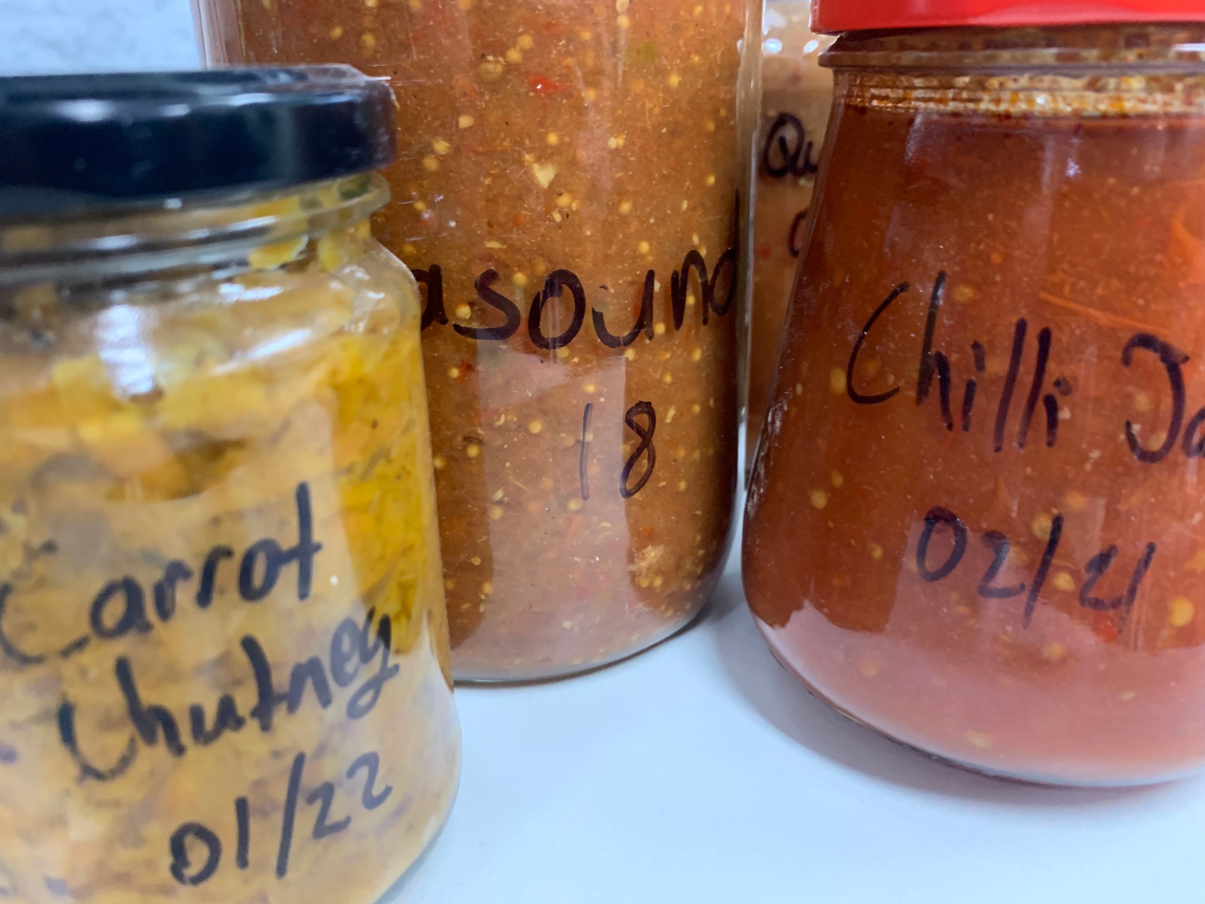 A variety of jars containing preserved vegetables and chutneys 