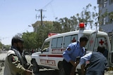 Afghans carry a casualty after a blast near a foreign base in Herat