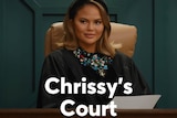 Chrissy sits in a chair behind a judge's bench.