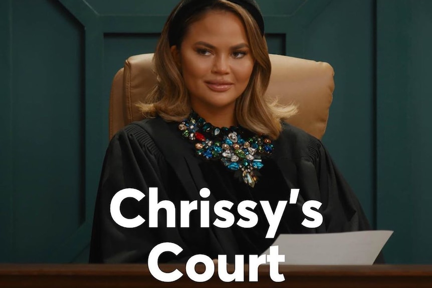 Chrissy sits in a chair behind a judge's bench.