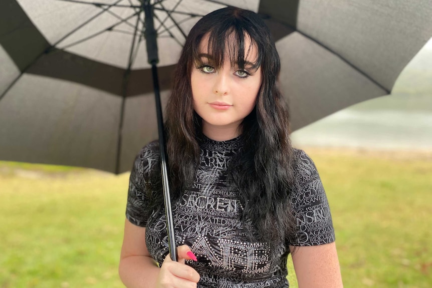 Une femme aux longs cheveux noirs sous un parapluie.