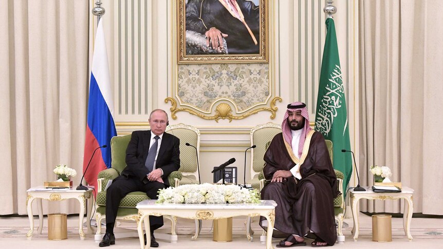Vladimir Putin (left) sits next to Mohammed bin Salman (right) in palace setting with portrait of Saudi royalty behind them
