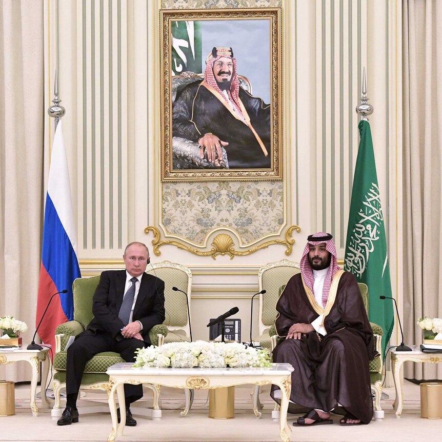 Vladimir Putin (left) sits next to Mohammed bin Salman (right) in palace setting with portrait of Saudi royalty behind them