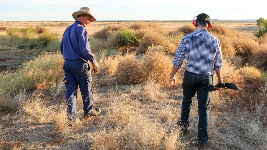 Robbie Katter and his friend, farmer Colin Muller, walk through a rural landscape in north Queensland, holding guns.