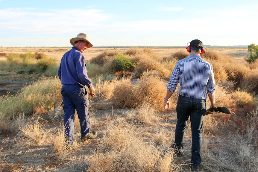 Robbie Katter and his friend, farmer Colin Muller, walk through a rural landscape in north Queensland, holding guns.