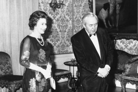 A black and white photo of the Queen in a formal dress and Harold Wilson in a tuxedo.