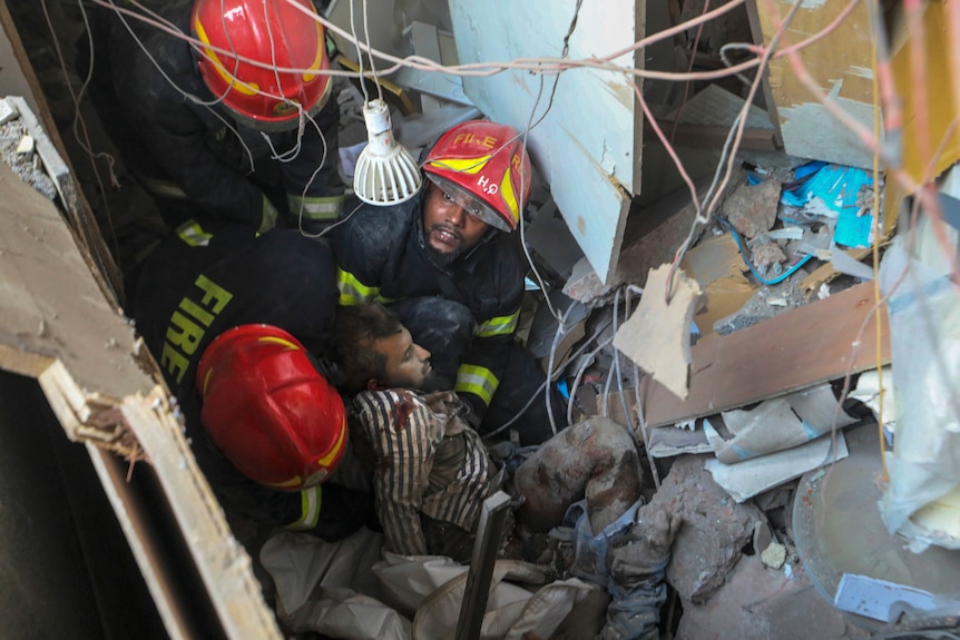 Fire officials rescue an injured person from the debris of a commercial building.