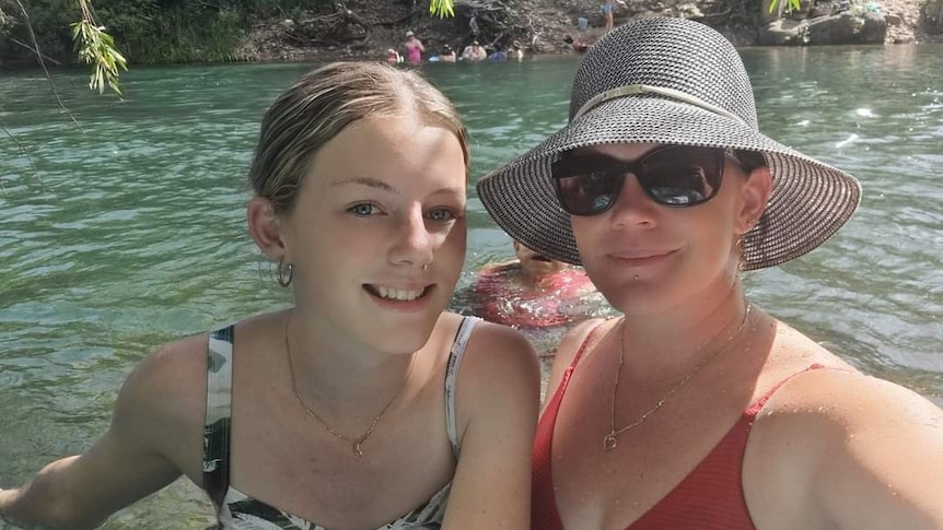 Mother and daughter take a photo in a creek. 