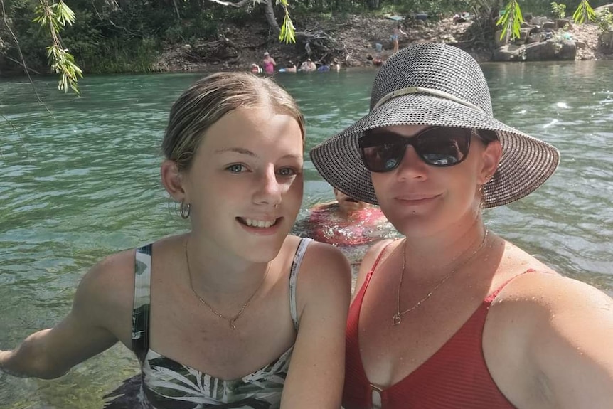 Mother and daughter take a photo in a creek. 