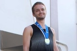 Matthew Dawson-Clarke wears a gold medal after winning a long distance race.