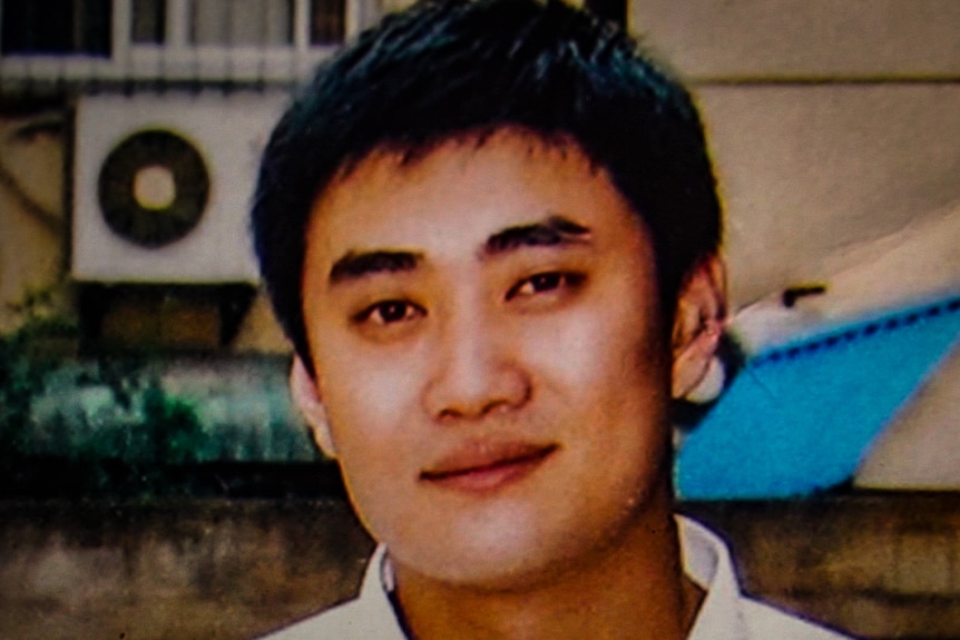 Close up picture of a young man with dark hair and a small smile on his face