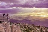 Wide view of two photographers standing on a lookout on top of Mt Wellington, photographing the sunrise.