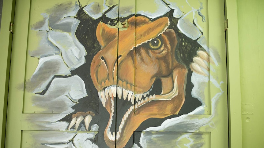A painting of a dinosaur that appears to be breaking through metal doors.