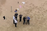 Six police officers gather on a beach.