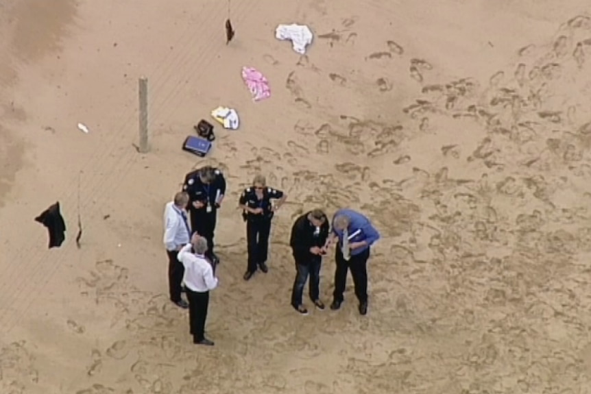 Six police officers gather on a beach.