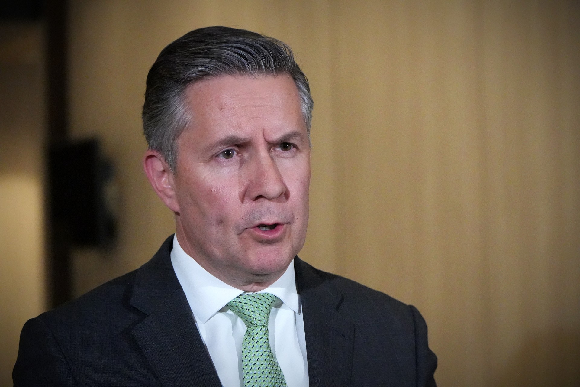 Sr. Butler fala em frente a uma parede bege.