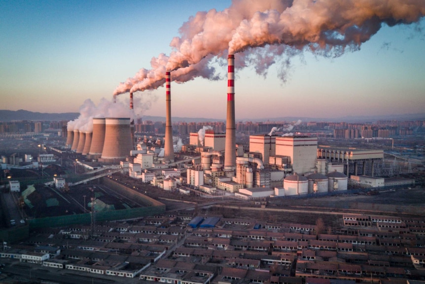 Smoke stacks billowing smoke at a power plant.