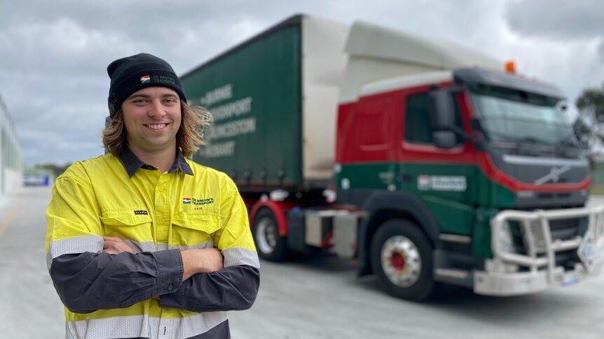 Tasmanian truck driver Tate Vanderfeen stands in front of his big parked truck.