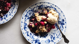 A serving of pear and blueberry crumble on a plate with a scoop of ice cream for a seasonal spring dessert.