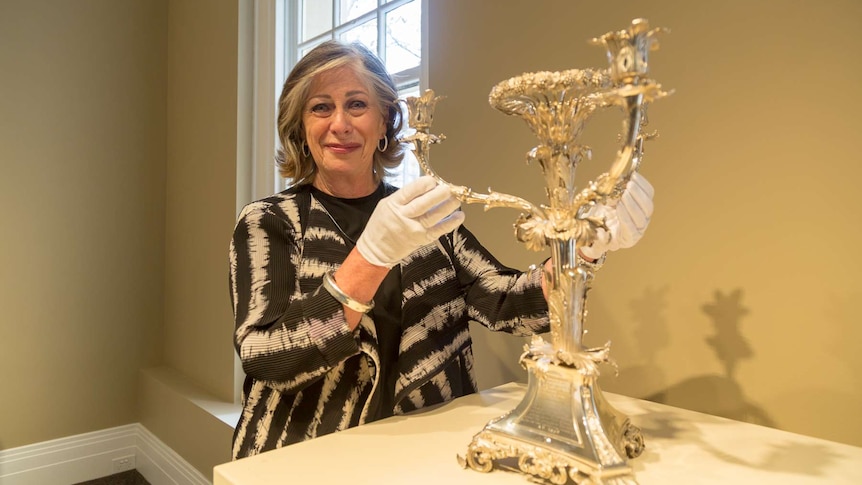 Cecilia Newman stands with a candelabra.