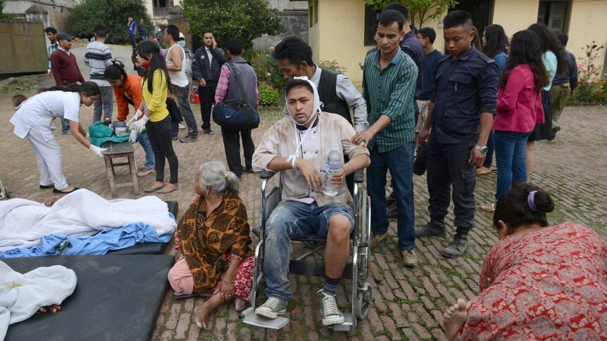 Nepalese people wheel an injured man