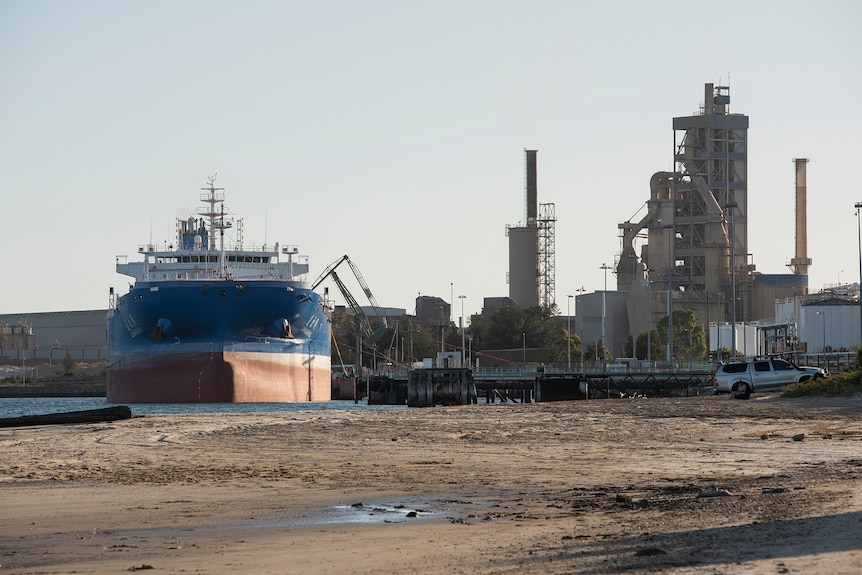 A large ship moored alongside a factory