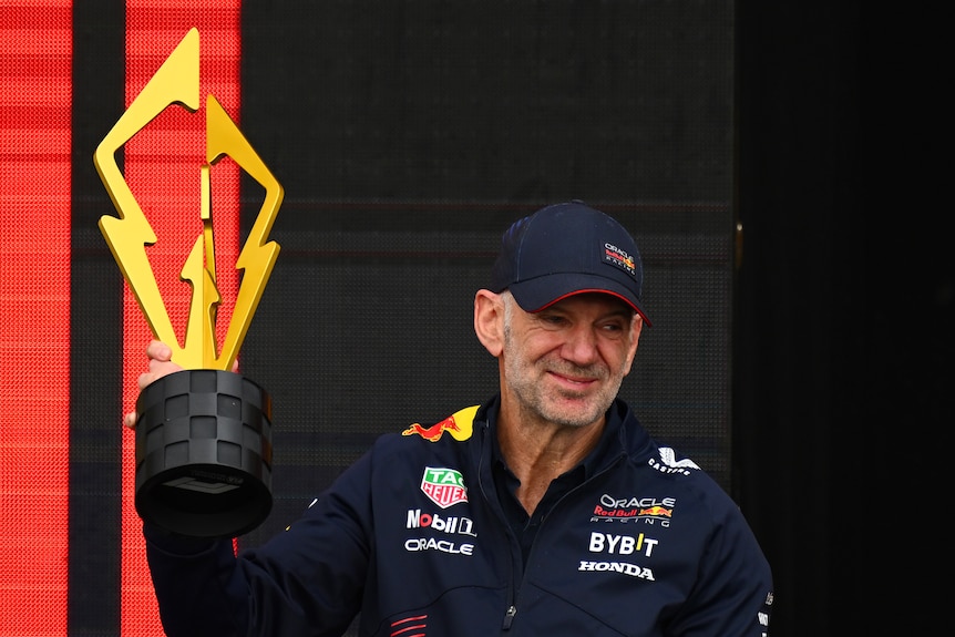 F1 staffer Adrian Newey, the Chief Technical Officer of Red Bull Racing celebrates on the podium with a trophy