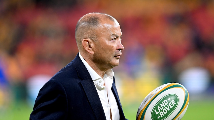 Eddie Jones holds a rugby ball in his hand