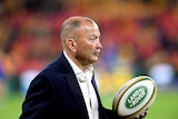 Eddie Jones holds a rugby ball in his hand
