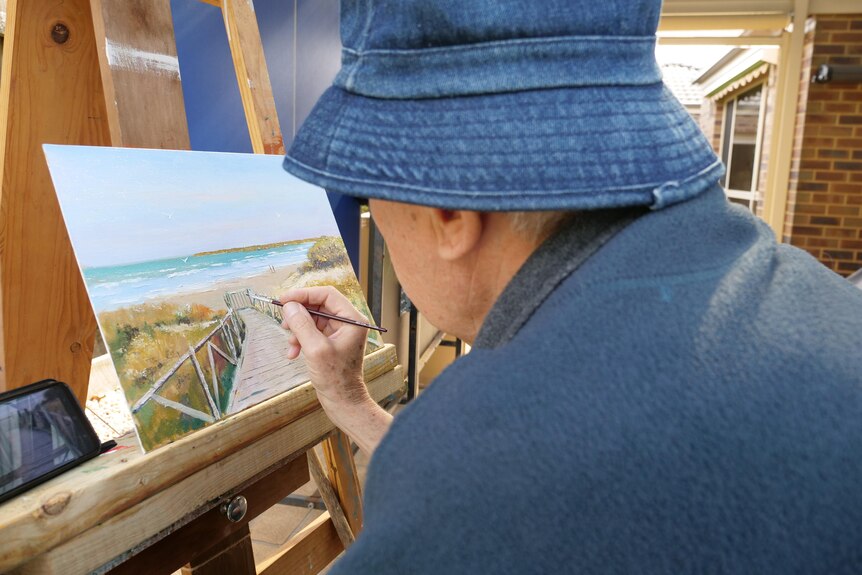 A man painting a beach scene