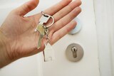A set of keys with a house keyring outside a front door, a rental that has been purchased by the tenant.