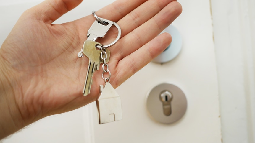 A set of keys with a house keyring outside a front door, a rental that has been purchased by the tenant.