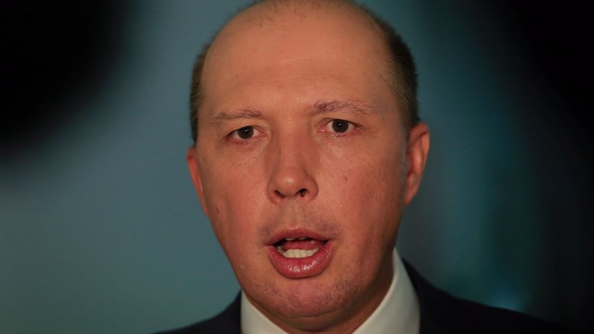 Peter Dutton captured with his mouth open mid sentence while wearing a navy suit and violet tie.